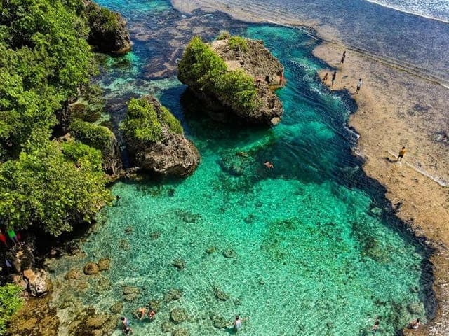Aerial view of swimmers in the clear turquoise Magpupungko Rock Pools in Pilar