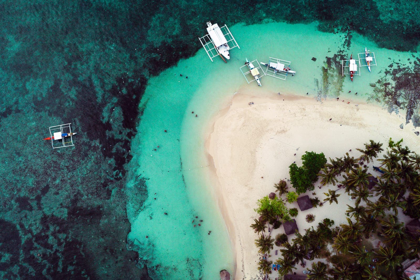 Aerial view of Guyam Island's white sand and bangka boats